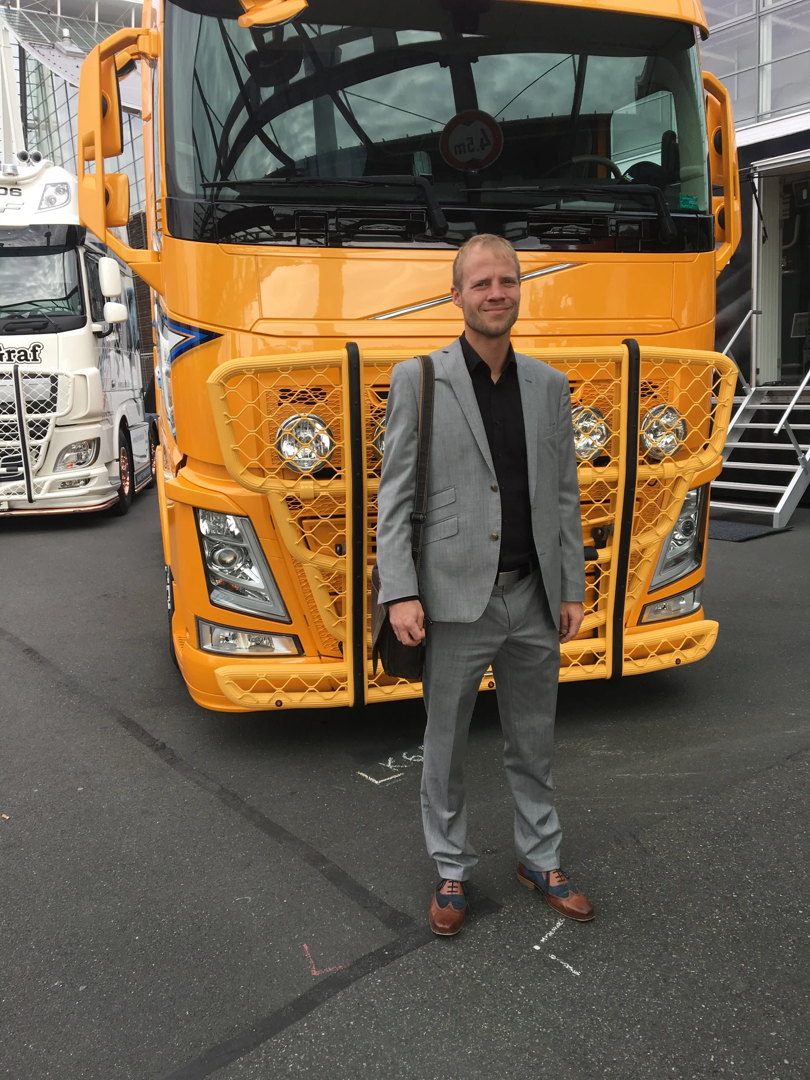 Björn Schallenberg vor einem gelben LKW auf einer Messe